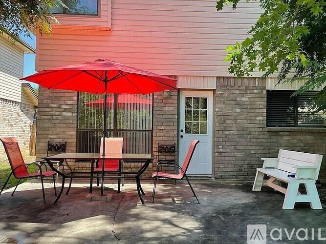 A patio with a table, chairs and an umbrella.