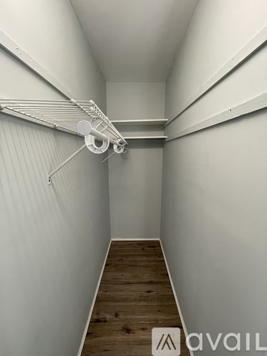 A long hallway with a white wall and a wooden floor.