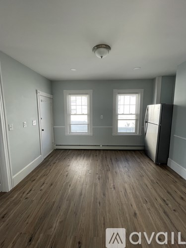 A room with wooden floors and two windows.