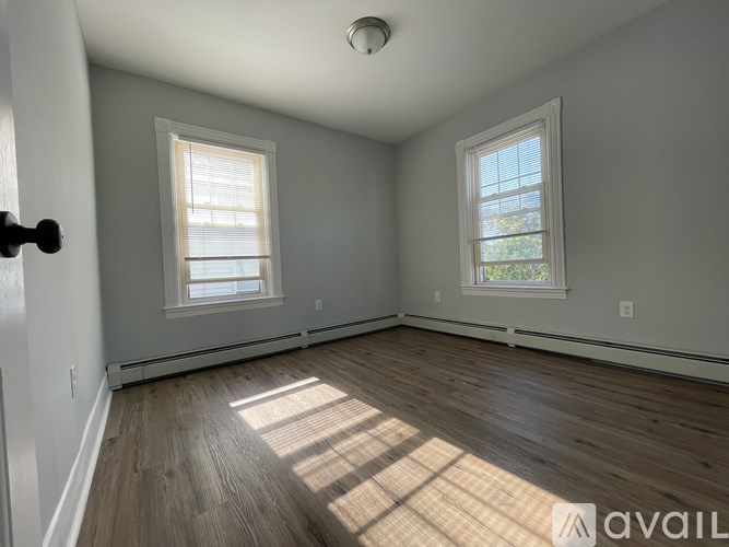 A room with wooden floors and two windows.