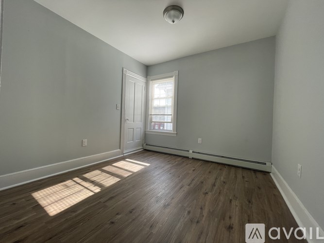 A room with wooden floors and a window letting in sunlight.