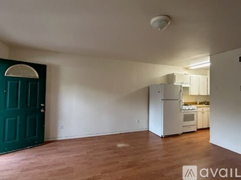 A kitchen with white appliances and a green door.