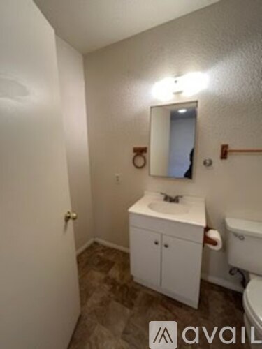 A small white bathroom with a toilet, sink and a mirror.