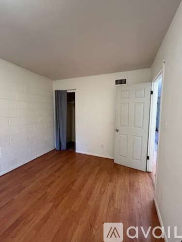 A room with wooden floors and white walls, with a door on the right side.