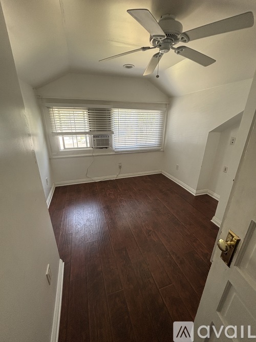 A room with a ceiling fan and wooden flooring.
