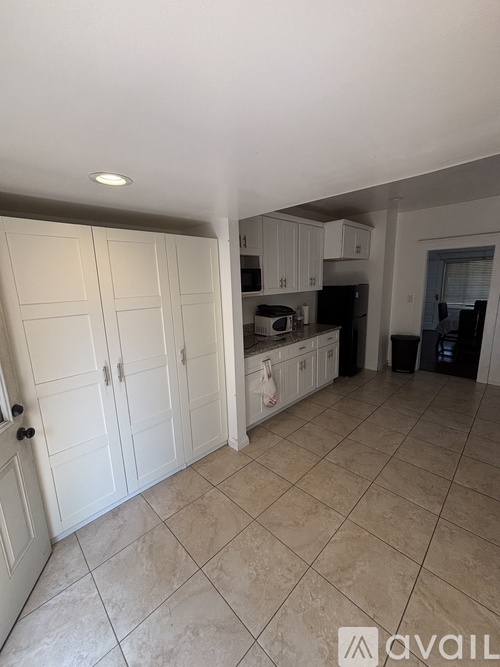 A kitchen with white cabinets and a tiled floor.