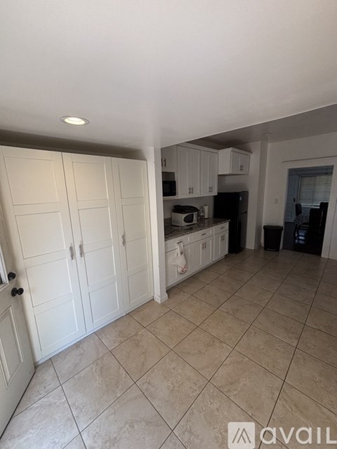 A kitchen with white cabinets and a tiled floor.