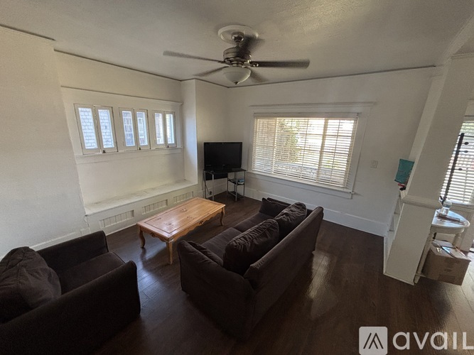 A living room with a brown couch, a wooden coffee table, and a ceiling fan.