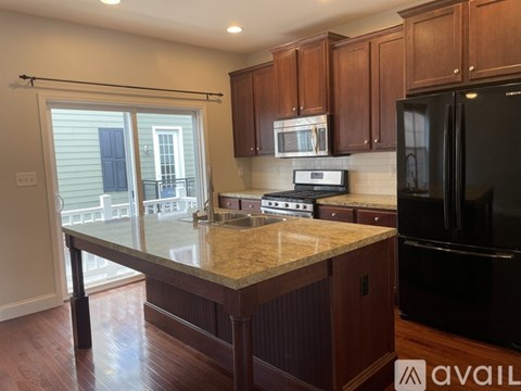 A kitchen with a black refrigerator, wooden cabinets, and a granite countertop.
