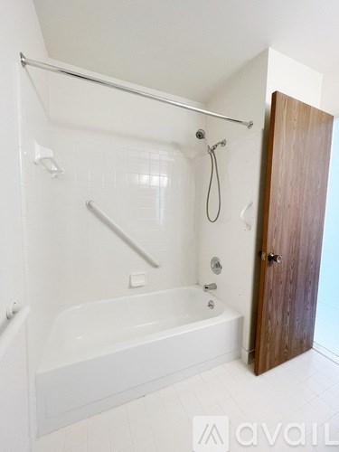 A white bathroom with a tub and a wooden door.