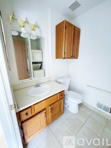 A bathroom with a sink, toilet, and wooden cabinets.