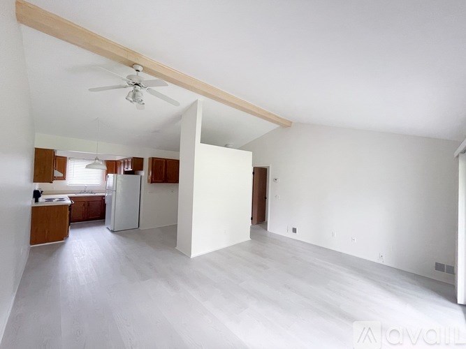 A spacious, empty room with a ceiling fan and light fixture.