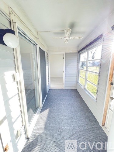 A sunny room with a ceiling fan and sliding glass doors.