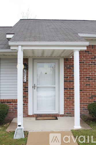 A white door is on the front of a house with a brick wall.