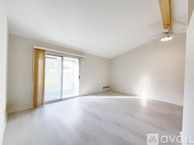 A spacious room with a sliding glass door and a ceiling fan.