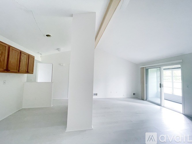 A large, empty room with white walls and a wooden cabinet on the left side.