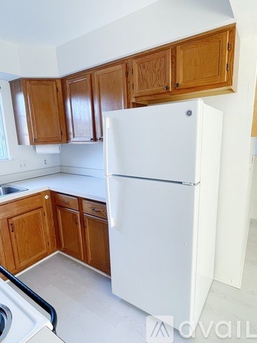 A white refrigerator in a kitchen with wooden cabinets.