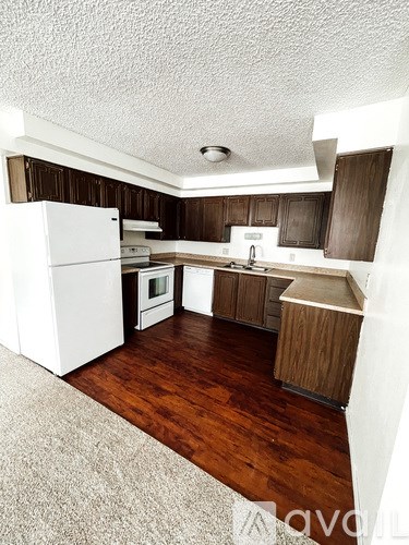 A kitchen with white appliances and wooden cabinets.