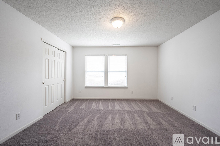 A room with a carpeted floor and a window with blinds.