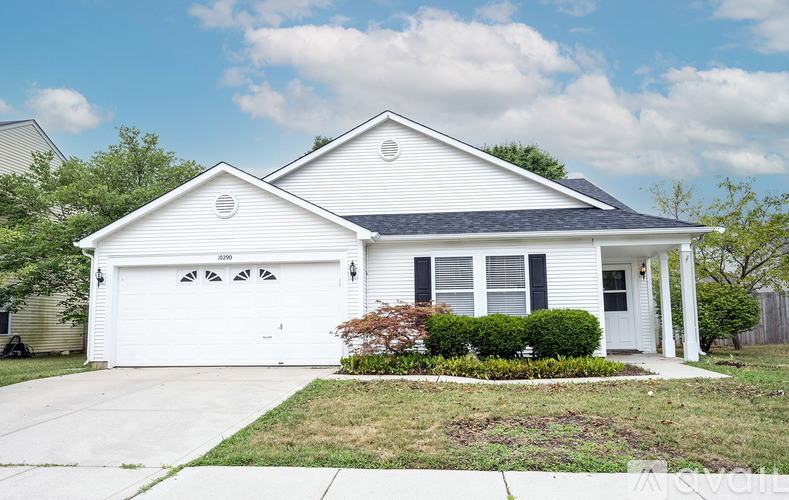 A white house with a grey roof and a black garage door.