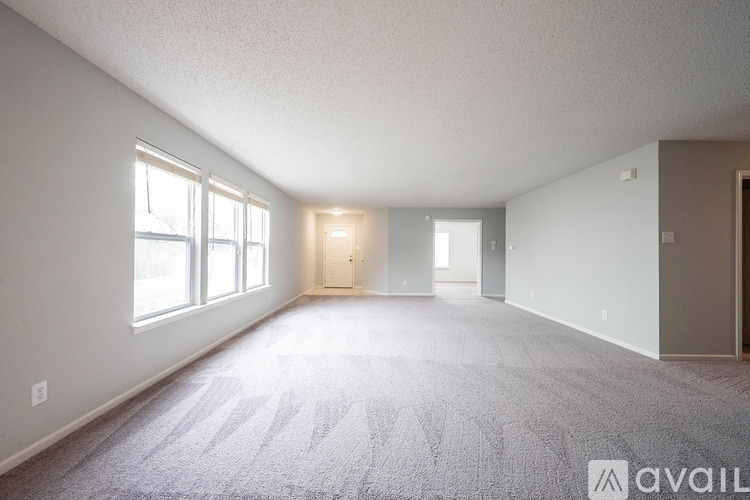 A spacious room with a carpeted floor and large windows.