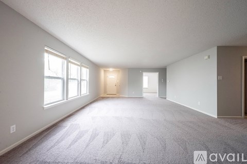 A spacious room with a carpeted floor and large windows.