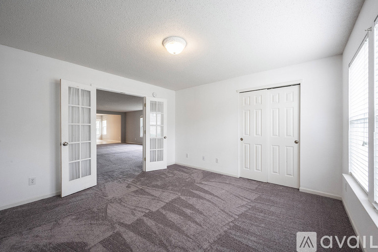 A room with a carpeted floor and a door on the right side.