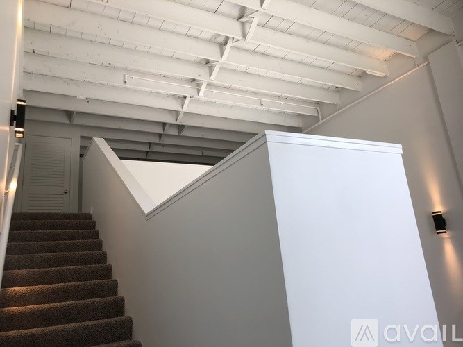 A staircase with a white wall and a brown carpet.