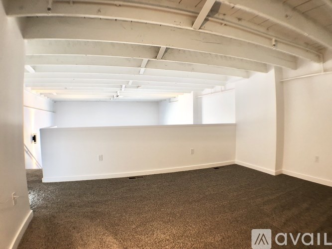 A spacious room with a carpeted floor and white walls.