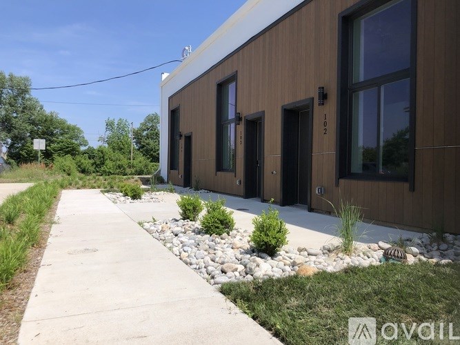 A modern building with a brown facade and a concrete walkway in front.