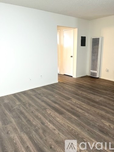 A room with wooden flooring and a doorway leading to another room.