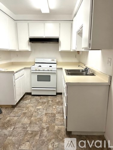 A kitchen with white cabinets and a white stove top oven.