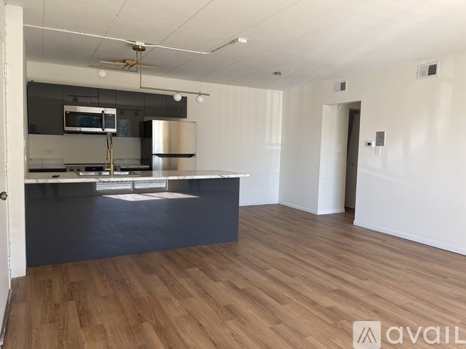 A kitchen with a black countertop and wooden flooring.