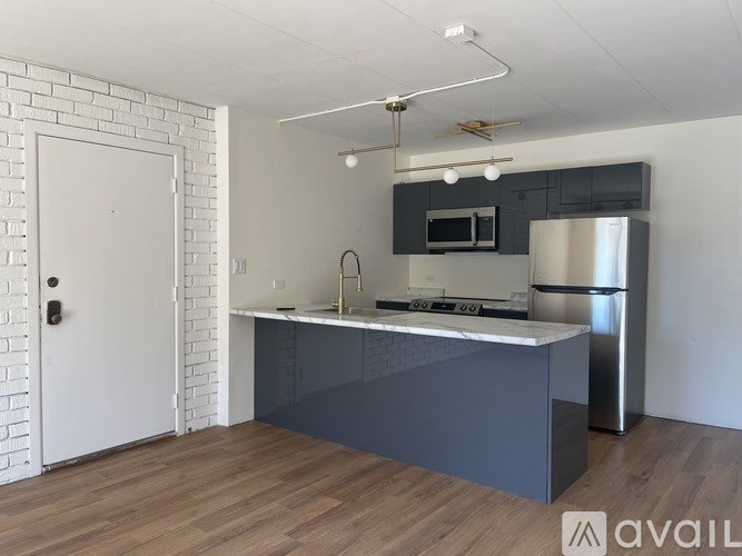 A kitchen with a white brick wall and a wooden floor.