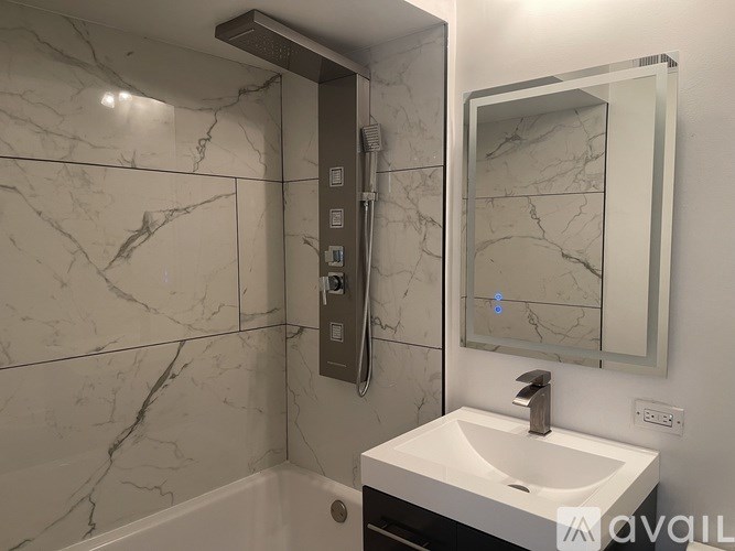 A bathroom with a marble tile wall and a white sink.
