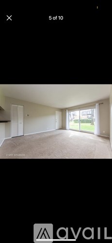 A room with a carpeted floor and a door leading outside.
