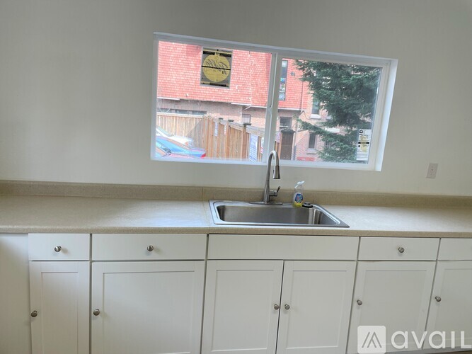 A kitchen with white cabinets and a window overlooking a backyard.