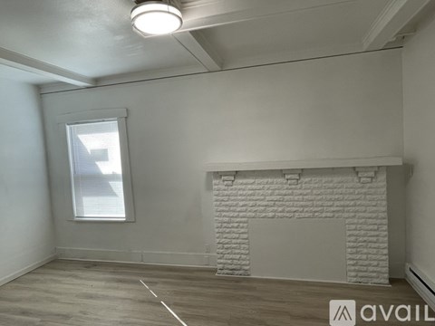 A room with a white brick fireplace and a window with blinds.