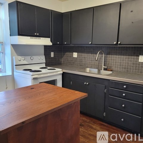 A kitchen with a white stove and black cabinets.