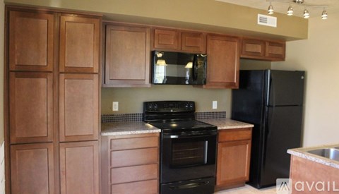 A kitchen with wooden cabinets and black appliances.