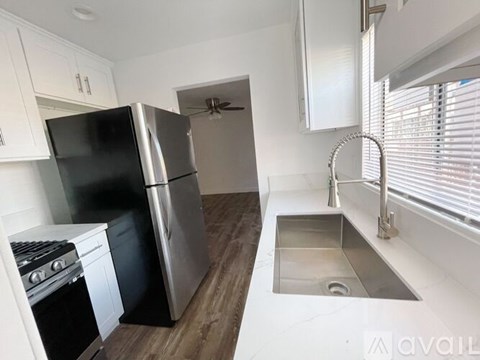 A kitchen with a black refrigerator, stainless steel dishwasher, and a stove top oven.