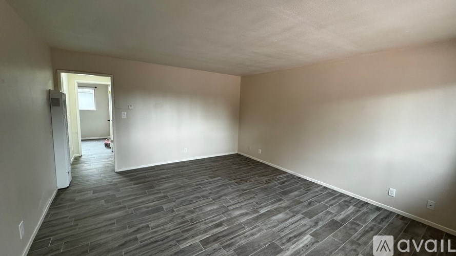 A room with wooden flooring and a doorway leading to another room.