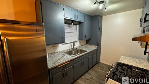 A kitchen with a stainless steel refrigerator and a granite countertop.