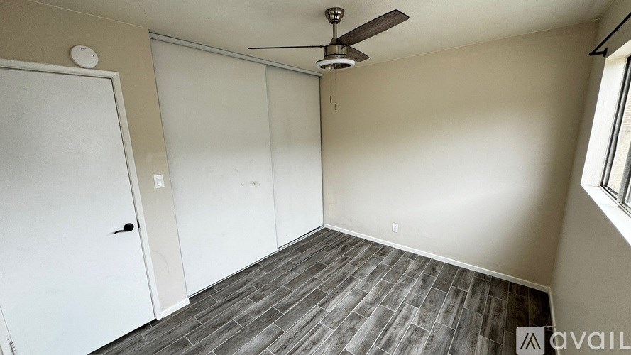 A room with a ceiling fan and a door.