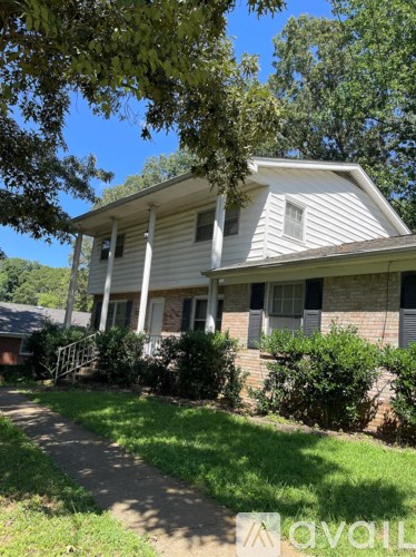 A house with a white porch and a tree in front.
