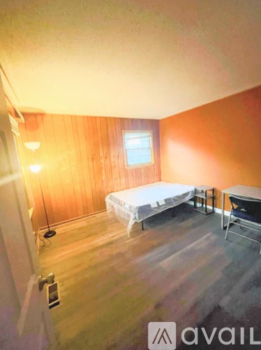 A bedroom with a bed, chair, and window.