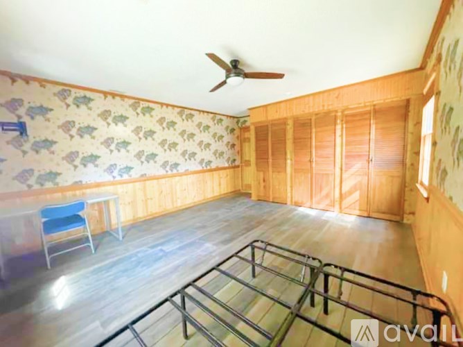 A room with a ceiling fan and a table with a blue chair.