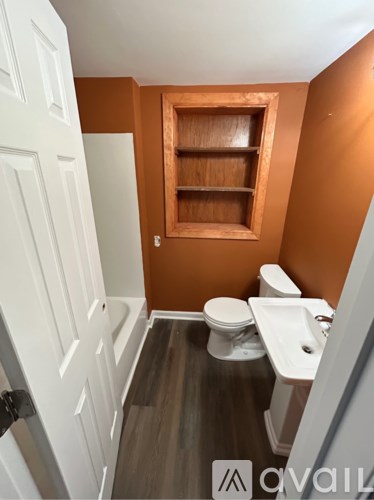 A small bathroom with a toilet, sink, and wooden cabinet.