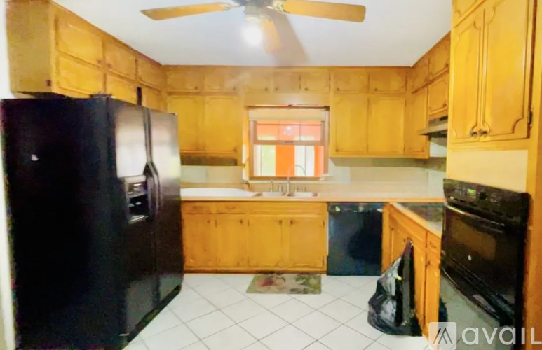 A kitchen with wooden cabinets and a black refrigerator.