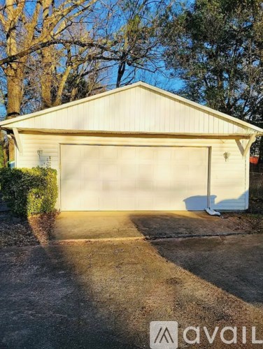 A white garage with a closed door and a driveway leading to it.